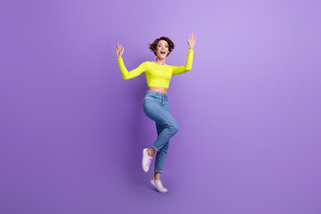 Fototapeta na wymiar Full size photo of overjoyed cheerful girl raise hands dancing have good mood isolated on violet color background
