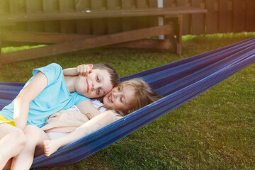Fototapeta na wymiar children brother and sister resting in the garden on a hammock