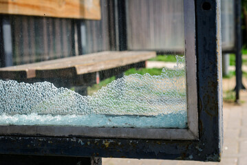 Vandalised Broken bus stop glass in the city.This is a manifestation of wild vandalism.Dangerous,crashed tempered glass pieces on ground.