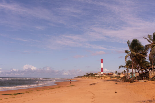 lighthouse's beach at Subauma city, cost of bahia, brazil. a person walking alone in a desert beach with view to lighthouse