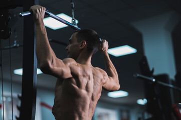 A man does a chest pulldown in the gym.