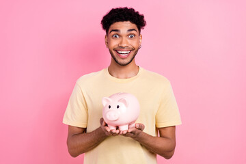 Fototapeta na wymiar Creative portrait of young overjoyed surprised guy hold piggy bank collect money for his future dream isolated on pink color background