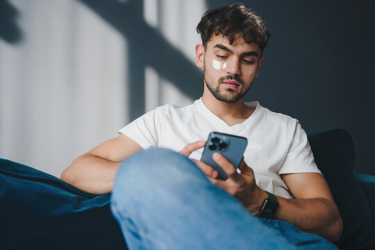 Young man using smartphone while sitting on sofa