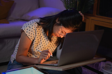 Young Asian female freelancer or student is working late at night. Concept of overload, overworked and burn out of work. Tired, exhausted, fatigue and sleepy from working in front od