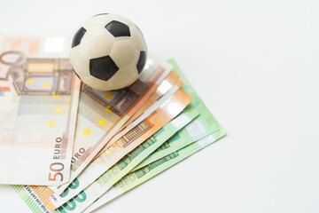 black and white colored soccer ball on a white background with euro banknotes, concept for sport and business