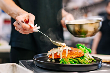 woman chef hand cooking salmon fish steak with asparagus and salad
