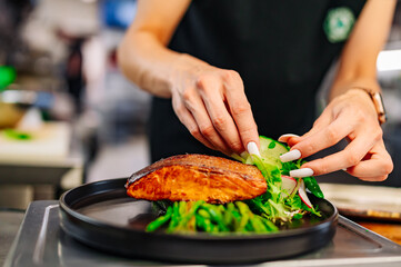 woman chef hand cooking salmon fish steak with asparagus and salad