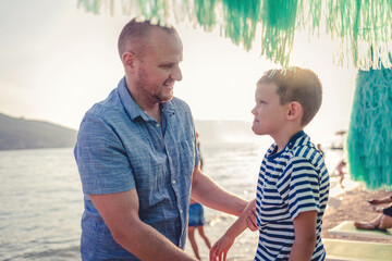 Father helping son dressing up on the beach.
