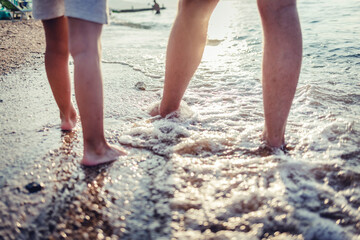 Feet of father and child walking together along the coast.