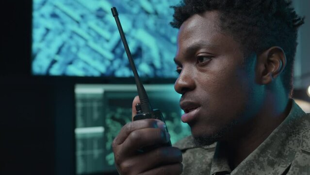 Close up of serious male African American military officer reporting on radio set indoor at night