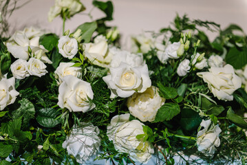 Festive table decorated with a composition of white flowers and greenery, and candles in the banquet hall. Table newlyweds covered with a tablecloth in the banquet area on a wedding party. Top view