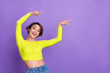 Photo of cheerful gorgeous girl indicate fingers empty space information blank isolated on violet...