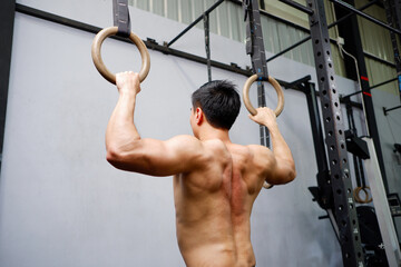 young man exercising with strong muscles working out in the gym fitness concept.
