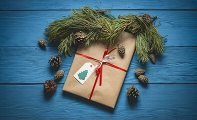 Gift handmade packaging with red ribbon under the pine branches