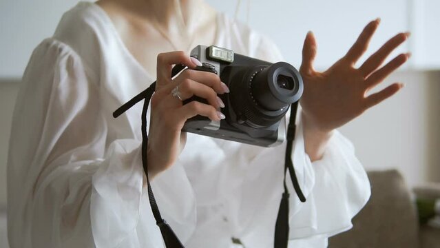 A woman shoots a wedding with a camera with instant development of pictures. The photographer holds the camera in his hands. Turn on the camera. Lens opening. Look through the viewfinder.