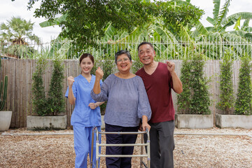 Happy Asian Senior Couple with Nurse Outdoors, Smiling at the Camera