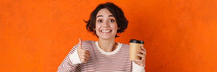Young brunette woman showing thumb up while drinking coffee