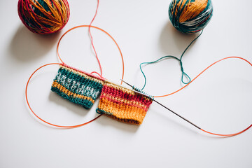 knitting with knitting needles by the magic loop method from multi-colored yarn on a white background © Анна Молько