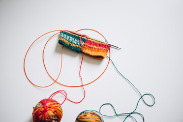 knitting with knitting needles by the magic loop method from multi-colored yarn on a white background