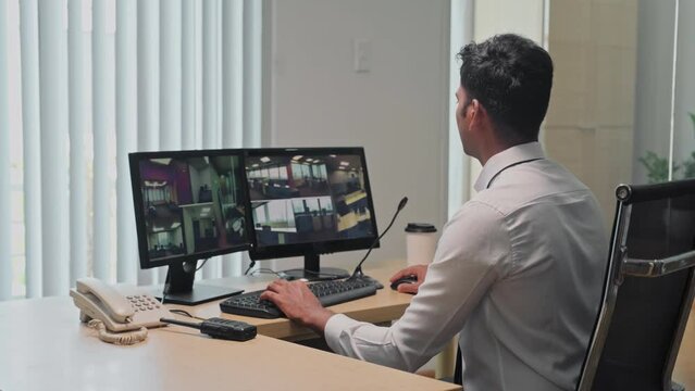 Security manager working in surveillance room sitting on workplace