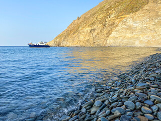 Blue bay (Mavi Koy) seascape next to Gokceada Yildiz Bay underwater national park and a boat moored in the bay. Imbros island, Canakkale, Turkey - obrazy, fototapety, plakaty