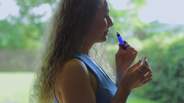 An attractive perfumer girl sniffs a jar of aroma oil and chooses a fragrance for herself. The concept of creating your own natural fragrance