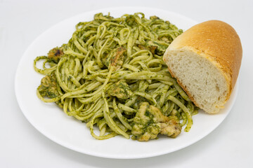 Linguini Pesto Pasta with Chicken on a White Plate with a Roll of Bread
