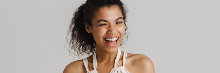 Black young woman in dress smiling and wink at camera