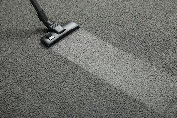 Vacuuming grey carpet. Clean area after using device. Space for text