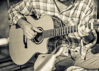 Close-up shot of guitarist playing country music, monochrome vintage style image.