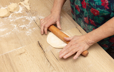 Close-up of an elderly woman rolling dough with a rolling pin