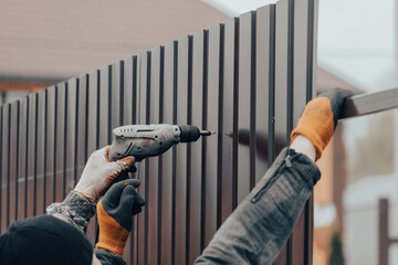 Workers install a metal profile fence - obrazy, fototapety, plakaty