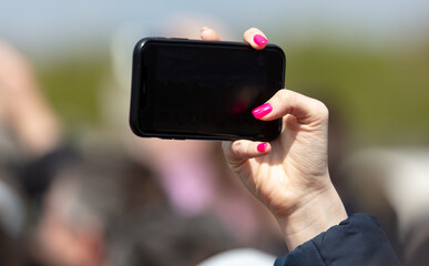 Close-up of female hand with pink manicure holding mobile phone