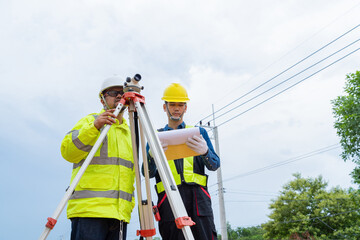 An engineer and an Asian contractor plan together on site to work on a rural highway.