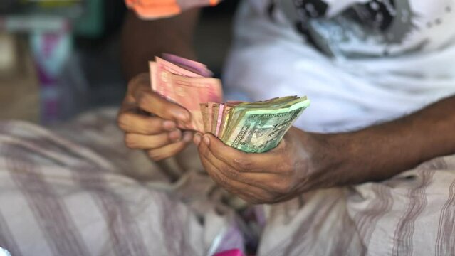 A man carefully counts a stack of Bangladeshi Taka banknotes, his fingers deftly moving across the bills. It is a reminder of the hard work and dedication that goes into earning and managing money