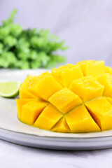 Mango sliced into cubes, close up. Yellow mango cut to cubes close-up with a lime slice, exotic indian ripe superfood. Raw food healthy eating concept. Sliced mango