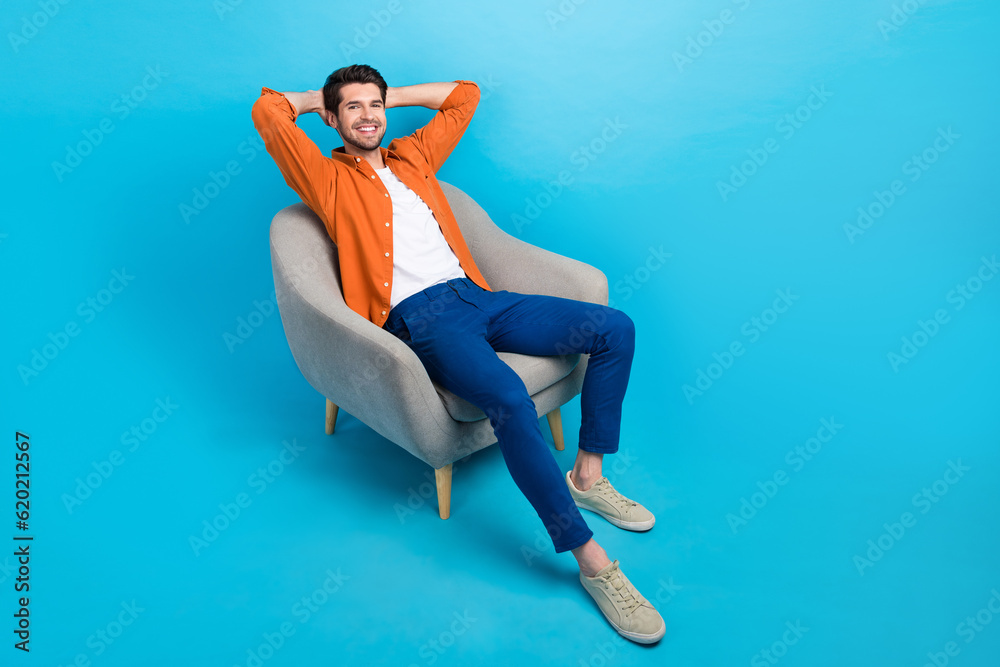 Poster full size portrait of cheerful peaceful young man sitting comfy soft chair hands behind head empty s