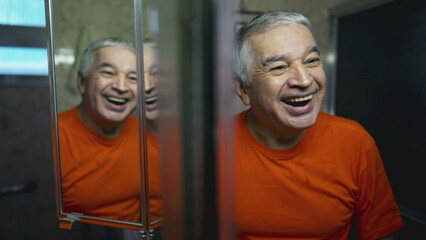 Happy senior man looking at himself in mirror reflection. Joyful emotion of elderly person laughing...