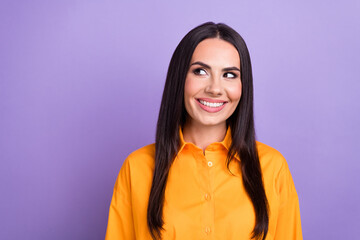 Photo of thoughtful smart business woman wearing orange shirt smiling look empty space brainstorming isolated on purple color background