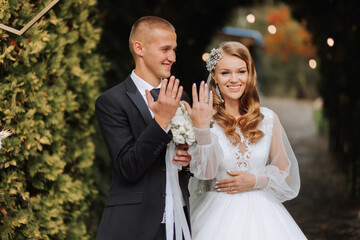 A young wedding couple at a wedding painting ceremony. The bride and groom show their wedding rings to the guests