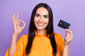 Portrait of young attractive brunette hair business woman show okey sign hold debit card high profit isolated on purple color background