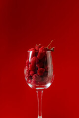 Glass of raspberries on the red background. 