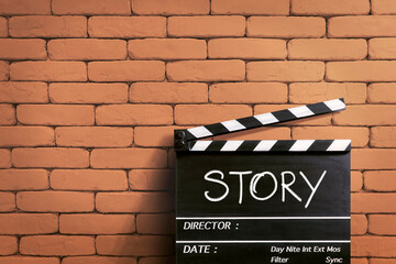 Story. handwritten on clapperboard or film slate. orange brick wall.