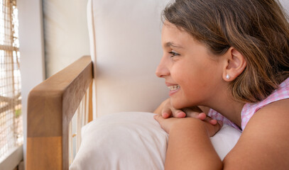 Side view profile Delighted happy child girl smiling lying on sofa outdoors.