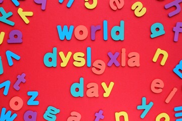 World dyslexia day words and random wooden colorful alphabet letters on red background. Learning difficulties, reading problem, dyslexia concept - obrazy, fototapety, plakaty