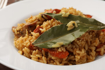 Delicious pilaf and bay leaves on plate, closeup