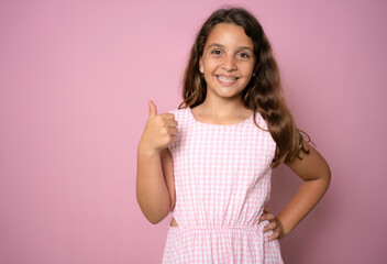Close up portrait of cute girl showing thumbs up.Isolated on pink background.