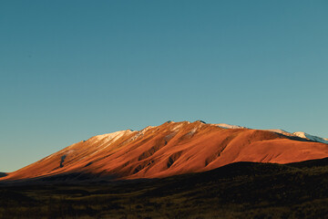 A snow capped mountain late on a sunny afternoon.