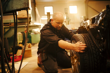 Obraz na płótnie Canvas Mature man working on a car in the workshop