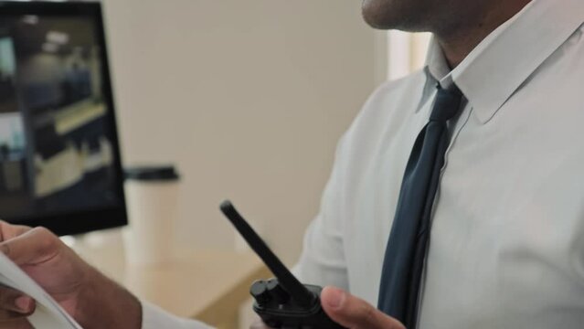 Close up shot of Indian security worker sharing information on walkie-talkie sitting in front of CCTV cameras at office